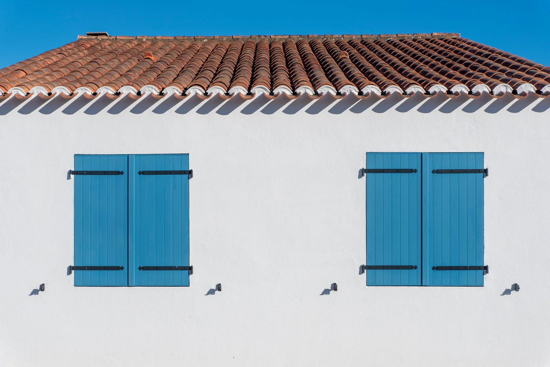 Maison blanche aux volets bleus et toit de tuiles rouges dans le sud-ouest de la France